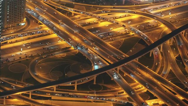 Top view of traffic cars on motorway. Multi-level illuminated road from bird eye view at night in city . Intersection of fork of expressway highways.