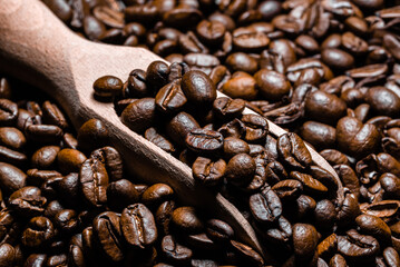 Freshly roasted coffee beans in scoop. Grained coffee background.