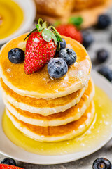 Pancakes with honey and berries on a plate.
