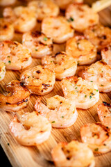 Grilled shrimp on a wooden cutting board.