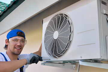 Repair of the outdoor air conditioning unit by a smiling specialist using a screwdriver. Master...