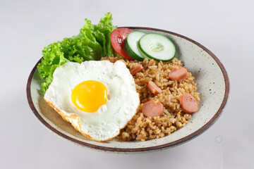 Nasi Goreng Sosis is Fried Rice with Sausages garnished with fresh cucumber and tomatoes slices.