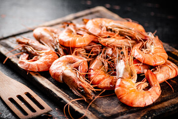 Cooked shrimp on a wooden cutting board. 
