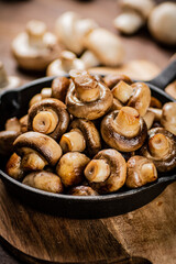 Fried mushrooms in a frying pan on a cutting board. 