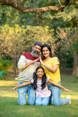 Fototapeta premium Young indian couple making home shape with hand with her daughter at park.