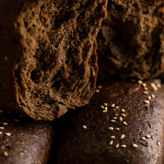 Rye malt bread. Broken loaf. Detailed structure of bread. Loaves sprinkled with sesame seeds. Close-up. 