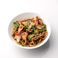 Udon noodles with chicken teriyaki, vegetables and sesame seeds. Asian cuisine. Dish on white background. Top view. 