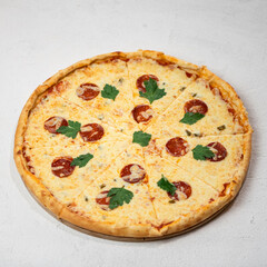 Pizza pepperoni with salami and cheese on white background. Pizza is cut into portioned pieces, decorated with parsley. Serving the dish. View from above. High quality photo