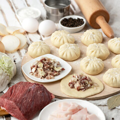 Chinese baozi on wooden cutting board. Cooking process. Dough ingredients, meat stuffing, spices and kitchen utensils on wooden table. 