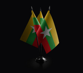 Small national flags of the Myanmar on a black background