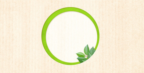 Round shape hole and green leaves on cardboard texture. Horizontal banner with eco paper texture. Paper cardboard background. Ecology and zero waste concept