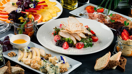 Restaurant banquet menu: Caesar salad, a plate with various types of cheeses, a meat plate with ham and salami