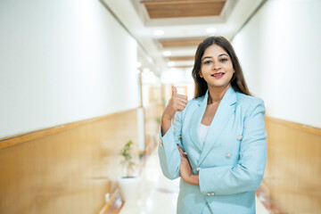 Fototapeta na wymiar Indian corporate woman showing thumps up at office
