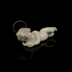 White figurine of baby Jesus on a black background with reflection. antique museum figurine of...