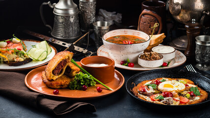Banquet table with fried potato pancakes with meat, Olivier salad, hodgepodge soup and potato pancake with champignons.