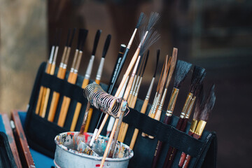 A set of hair paintbrushes in an artist's case and a pot of oil paint