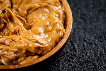 Peanut butter in a wooden plate on the table. 