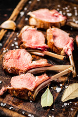 Rack grilled lamb on a cutting board with bay leaves. 