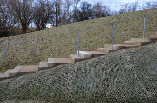 outdoor park stairs on a slope. jute mat protects against erosion. seed spraying in a cellulose hydroseed solution. sandstone steps and galvanized railings. grind trowel between stages, stage, step