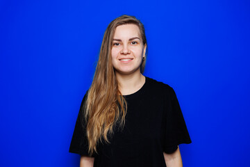 Happy beautiful woman without makeup in a black t-shirt showing different emotions on a blue background. Natural female beauty without cosmetics, naturalness. The concept of beauty