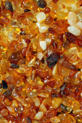 Amber texture background, small stones yellow orange gradient color. Natural gemstone mineral for jewelry. Top view Amber textured fon. Sunstones pieces ancient resin. Transparent pieces gem.