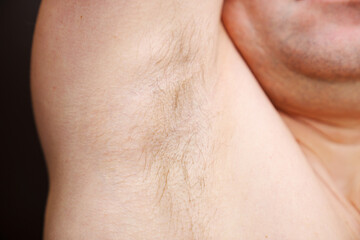 close-up. a man sniffs an unshaven armpit. the concept of the smell of sweat and deodorants for men.
