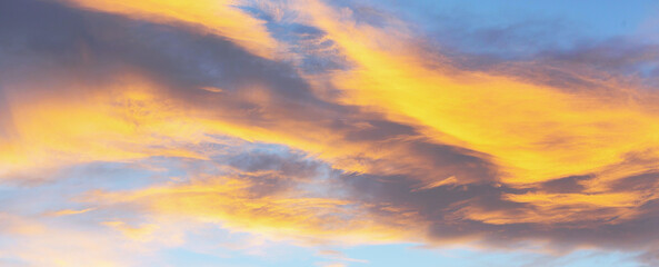 Dramatic cumulus clouds on sunny day at sunset painted with sun. Banner. Atmosphere multicolor background or wallpaper