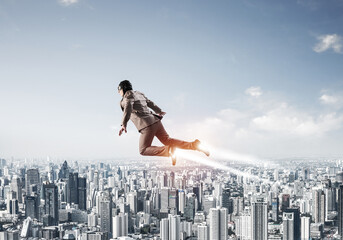 Businessman in suit and aviator hat flying in sky