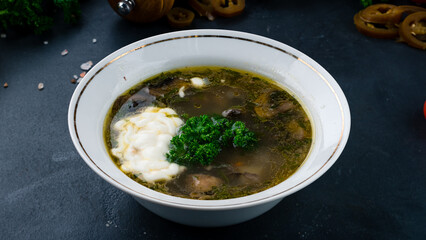 Champignon soup with sour cream and greens in bowl.