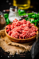 Minced meat in a plate on burlap with spices. 