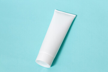 A white colored cream bottle laying out on the top of a blue paper