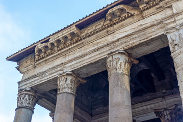 Fragment of columns and roof in Rome, in the blue sky.  Important ancient buildings, fragment of the Temple.