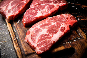 Raw pork steak on a wooden cutting board. 
