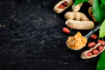 A spoonful of peanut butter on a table with leaves.