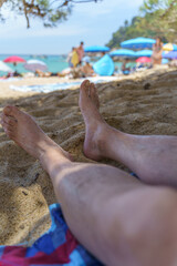 Man relaxing in shadow of a tree on the beach. Summer sunny vacation