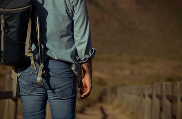 Fototapeta premium Adult man with backpack walking on dirt road