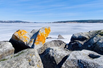 Stones on the beach of Andresön island by the frozen Storsjön lake - 563834507