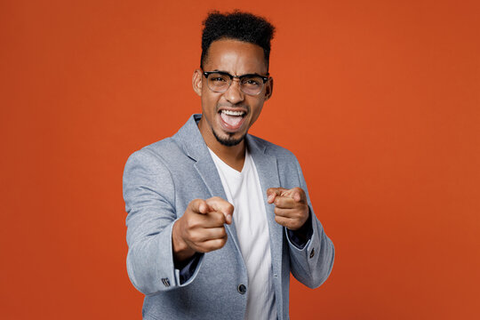 Young employee business man corporate lawyer wear classic formal grey suit shirt glasses work in office point index finger camera on you motivating encourage isolated on plain red orange background.