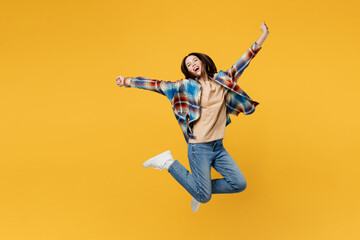 Full body young fun carefree overjoyed woman wear blue shirt beige t-shirt jump high with outstretched hands look camera isolated on plain yellow background studio portrait. People lifestyle concept.