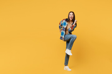 Fototapeta na wymiar Full body side view cool fun overjoyed young smiling woman wears blue shirt beige t-shirt look camera do winner gesture isolated on plain yellow background studio portrait. People lifestyle concept.