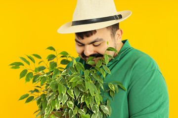 Concept of people, young fat man with plant on yellow background