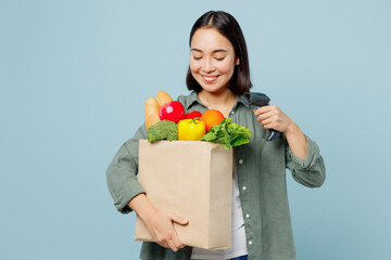 Fototapeta na wymiar Young smiling happy woman wear casual clothes hold brown paper bag scanning food products check bar code isolated on plain blue background studio portrait. Delivery service from shop or restaurant.