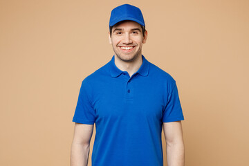 Professional smiling fun satisfied happy delivery guy employee man wear blue cap t-shirt uniform workwear work as dealer courier look camera isolated on plain light beige background. Service concept.