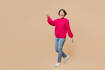 Full body sideways profile fun happy caucasian young woman wearing pink sweater walk going point...
