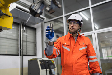 Caucasian technician engineer man holding spare with checking machine arm robot at factory	