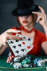 poker player sits at a poker table with cards in her hands and poker chips on the table