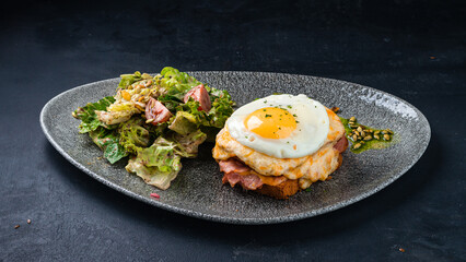 Fried bacon with cheese and egg on toast with a salad of cherry tomatoes, lettuce, spinach, pumpkin seeds and sauce.