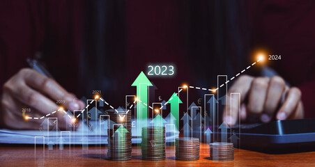 Businessman planning business growth in 2023 and beyond. with virtual holographic charts Calculate investment earnings and profits and increase them with positive growth indicators, stocks, profits.