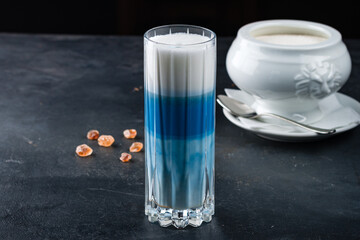 Blue matcha latte tea in a glass with sugar.