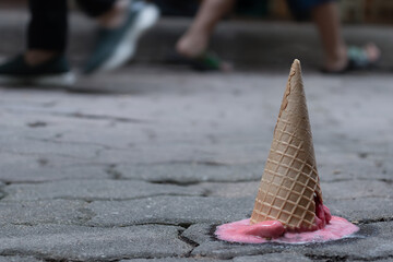 Children make fallen pink sorbet ice cream with cracking cone on the old cement ground background....